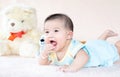 Closeup asian baby infant laying comfortably on bed playing with bear doll on softness cushion,Baby development concept