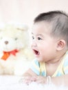 Closeup asian baby infant laying comfortably on bed playing with bear doll on softness cushion,Baby development concept