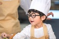 Closeup of Asian cute little boy wearing chef hat and apron with mother in home kitchen. Thai people and lifestyles concept. Job Royalty Free Stock Photo