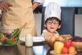 Closeup of Asian cute little boy wearing chef hat and apron with mother in home kitchen. Thai people and lifestyles concept. Job Royalty Free Stock Photo