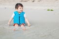 Closeup cute asian kid with life jacket enjoy on beach textured background