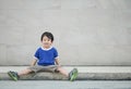 Closeup happy asian kid with smile face sit at pathway on marble stone wall textured background with copy space