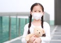 Closeup asian little child girl hugging teddy bear doll with wearing mask to against corona virus and air pollution in Bangkok Royalty Free Stock Photo