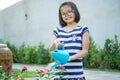 Closeup Asian little girl watering the colourful blossom flowers by watering can