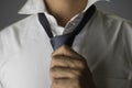 Closeup on an Asian man tying a grey skinny necktie