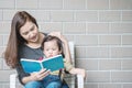 Closeup asian mother is teaching her son to read a book on stone Royalty Free Stock Photo