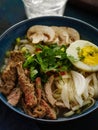 Closeup of Asian ramen soup with beef, egg, chives in bowl.