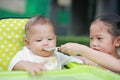 Closeup Asian sister feeding food for her little brother on the plastic chair in the garden Royalty Free Stock Photo