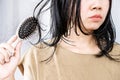 Asian woman experiences hair loss while brushing wet hair with a comb Royalty Free Stock Photo