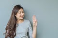 Closeup asian woman holds up three fingers with smile face on blurred cement wall textured background with copy space Royalty Free Stock Photo