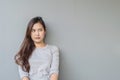 Closeup asian woman sitting and look at space with thinking face on blurred cement wall textured background with copy space