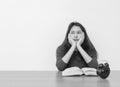 Closeup asian woman sitting for read a book with bored emotion and thinking face on wood table and white cement wall textured back Royalty Free Stock Photo