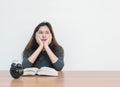 Closeup asian woman sitting for read a book with bored emotion and thinking face on wood table and white cement wall textured back Royalty Free Stock Photo