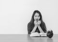 Closeup asian woman sitting for read a book with scary face and shock emotion on wood table and white cement wall textured backgro Royalty Free Stock Photo