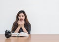 Closeup asian woman sitting for read a book with scary face and shock emotion on wood table and white cement wall textured backgro