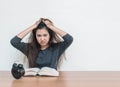 Closeup asian woman sitting for read a book with strain face emotion on wood table and white cement wall textured background with Royalty Free Stock Photo