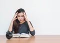 Closeup asian woman sitting for read a book with strain face emotion on wood table and white cement wall textured background in wo Royalty Free Stock Photo