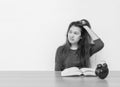 Closeup asian woman sitting for read a book with strain face emotion on wood table and white cement wall textured background in bl Royalty Free Stock Photo