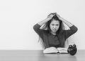 Closeup asian woman sitting for read a book with strain face emotion on wood table and white cement wall textured background in bl Royalty Free Stock Photo