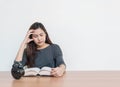 Closeup asian woman sitting for read a book with strain face emotion on wood table and white cement wall textured background in wo Royalty Free Stock Photo