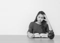 Closeup asian woman sitting for read a book with strain face emotion on wood table and white cement wall textured background in wo Royalty Free Stock Photo