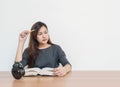 Closeup asian woman sitting for read a book with thinking face emotion on wood table and white cement wall textured background wit Royalty Free Stock Photo