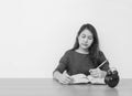 Closeup asian woman sitting for read a book in work concept on wood table and white cement wall textured background in black and w Royalty Free Stock Photo