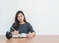 Closeup asian woman sitting for read a book in work concept on wood table and white cement wall textured background with copy spac Royalty Free Stock Photo