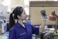Closeup Asian woman technician engineer hold and looking check example small gear in industrial Royalty Free Stock Photo