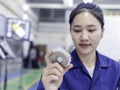 Closeup Asian woman technician engineer hold and looking check example small gear in industrial Royalty Free Stock Photo