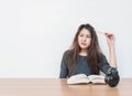 Closeup asian woman tired from reading a book with boring face emotion in work concept on wood table and white cement wall texture Royalty Free Stock Photo