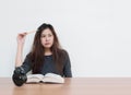 Closeup asian woman tired from reading a book with thinking face emotion in work concept on wood table and white cement wall textu