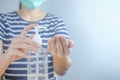 Closeup Asian woman wearing protective mask using hand sanitizer by pumping alcohol gel. Cleaning her hands with sanitizer gel. in Royalty Free Stock Photo