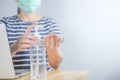 Closeup Asian woman wearing protective mask using hand sanitizer by pumping alcohol gel. Cleaning her hands with sanitizer gel. in Royalty Free Stock Photo