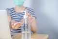 Closeup Asian woman wearing protective mask using hand sanitizer by pumping alcohol gel. Working from home. Cleaning her hands Royalty Free Stock Photo