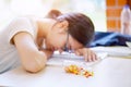 Closeup Asian young female student was sick and fell asleep on the table, and the medicine bottle spilled