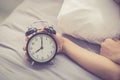 Closeup asian young woman turn off alarm clock in good morning, wake up for sleep with girl holding alarm clock