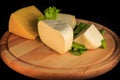 closeup assorted hard cheese on round wooden board