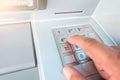 Closeup ATM machine and finger hand entering pressing password for withdrawing money banknotes Royalty Free Stock Photo