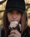 Closeup of an attractive brunette holding a bouqet of small white hand picked flowers on her lips, bright colorful amber eyes