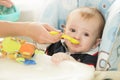 Closeup of baby boy sitting behind table at highchair and eating Royalty Free Stock Photo