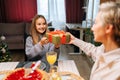 Closeup back view of loving grandmother giving festive box with Christmas present to adorable granddaughter sitting at Royalty Free Stock Photo