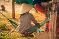 Backside Woman in Straw Hat Sits in Hammock in Vietnam