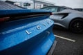 Closeup of the backside of the wet, blue Lotus automobile with a Lotus logo on the outside