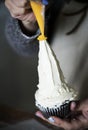 Closeup of baker decorating a cupcake