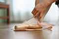 Closeup ballerina tying pointe shoes in dance studio. Art, dance, people and inspiration concept