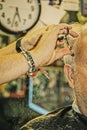 Closeup of barber with bead bracelet trimming older man`s hair with sissors in old fashione barber shop - cut hair falling onto