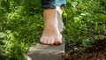 Closeup of bare female feet walking on wooden board through dense grass in garden. Concept of freedom. loving nature and