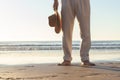 Closeup of barefoot Caucasian mans legs standing at the beach