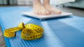 Closeup of barefoot woman weighting on scales on fitness mat after doing exercise or fitness. Concept of dieting